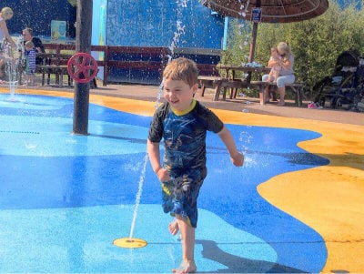 Child running around a wet play area