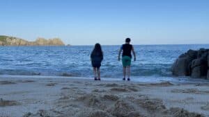 Two children on a beach standing at the waters edge