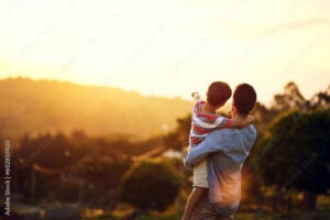 Father, child and pointing to sunset in nature for travel, holiday or weekend getaway outdoors. Back of dad holding kid enjoying the future, sunrise or horizon for family bonding on mockup space