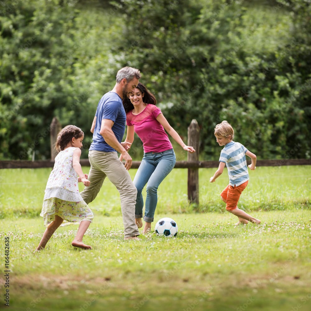 Cheerful family playing football in a garden