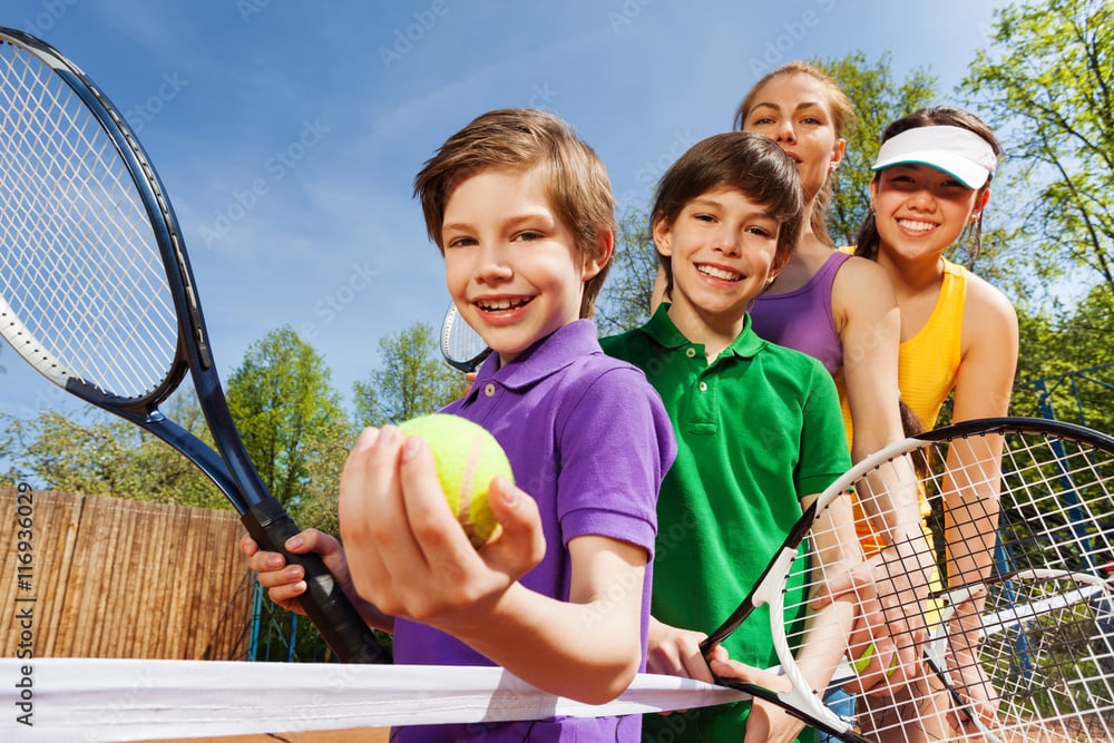 Family playing tennis holding rackets and ball