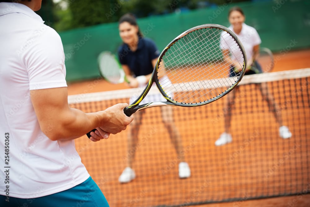 Group of healthy happy friends at the club playing tennis