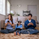 Family members using digital devices in living room