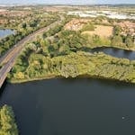 Scenic aerial view of Caldecotte Lake, roads, and countryside in England, showcasing natural beauty.