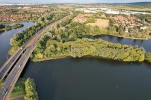 Scenic aerial view of Caldecotte Lake, roads, and countryside in England, showcasing natural beauty.