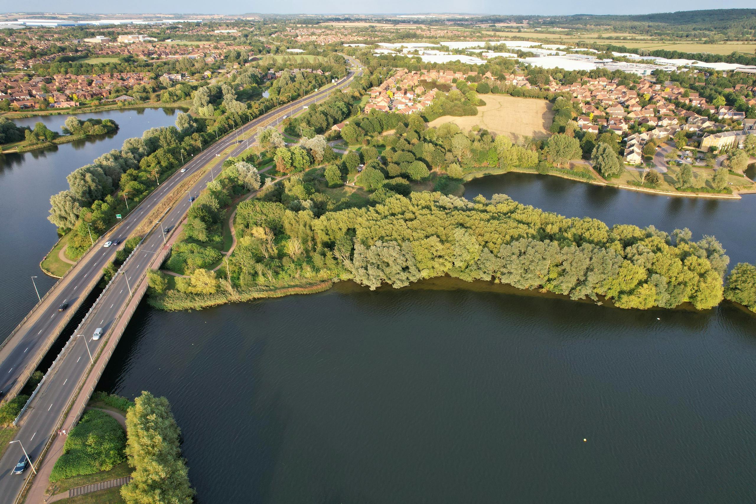Scenic aerial view of Caldecotte Lake, roads, and countryside in England, showcasing natural beauty.
