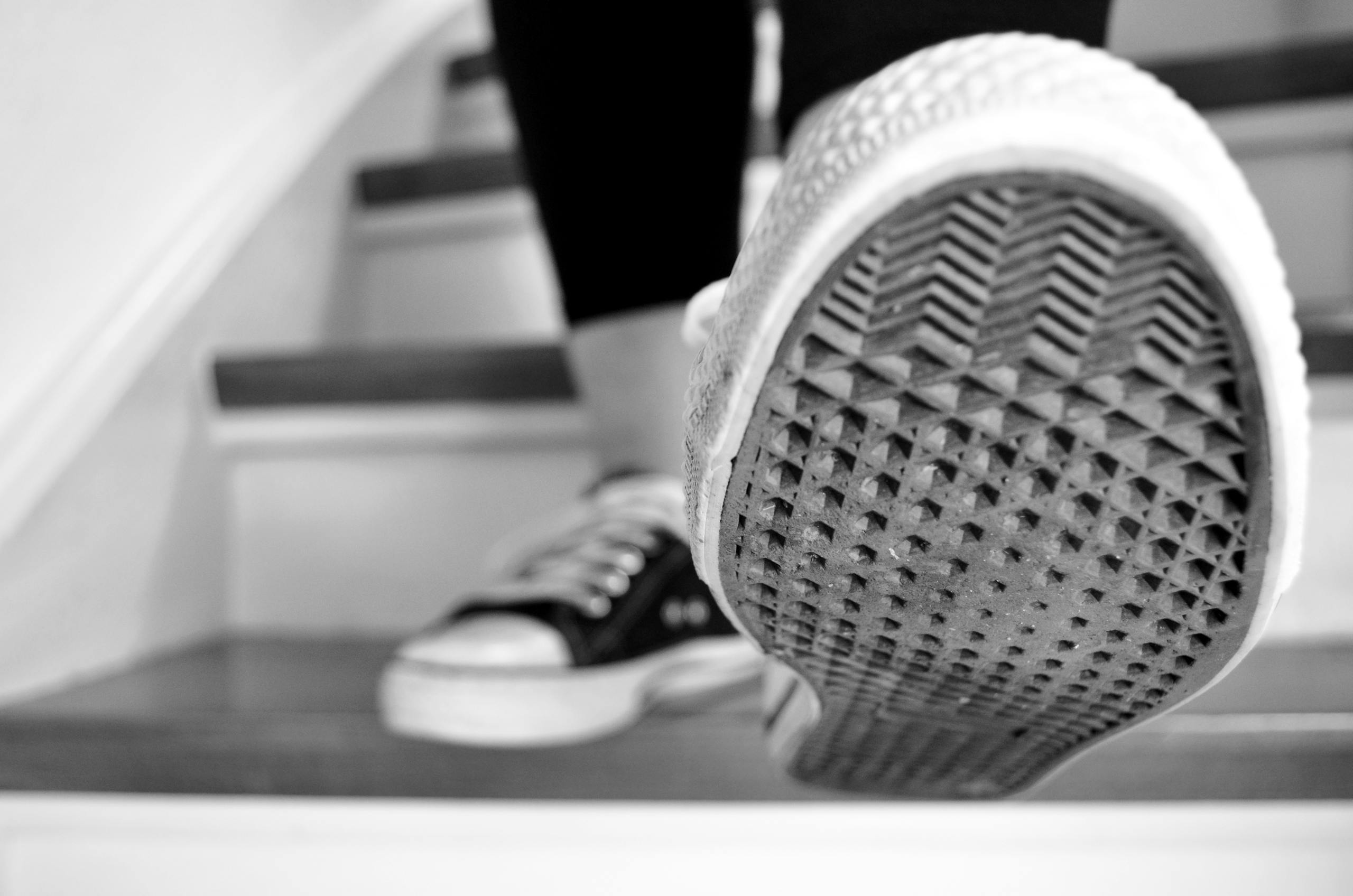 Black and white shot of sneakers ascending stairs, showcasing the sole pattern.