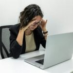 Tired Young Female Employee Feeling Stressed, Headache, and Burnout from Computer Work